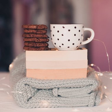 Katlanmış örgü süveter, açık kitaplar, bir fincan taze çay abd lezzetli çikolatalı kurabiyeler odada Noel ışıklarıyla masada duruyor. İyi sabahlar. Okul zamanı.. 