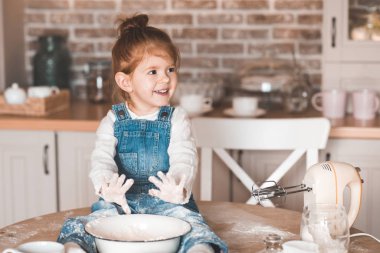 Gülen kız 3-4 yıldır masada oturmuş un ve mikserle pasta yapıyor. Çocukluk. 