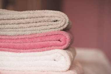 Otel odasında yatakta kalan yumuşak havlular yığını yakın. Seçici odak. 