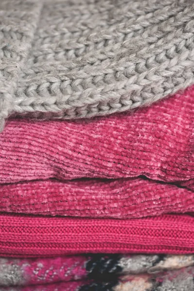 Stack of folded knitted clothes in wardrobe closeup. Winter season.