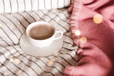 Yatakta bir fincan kahve ve yakın çekim ışıkları. Günaydın.. 