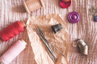 Tekstil kapağında iğne, düğme ve yüksük bulunan iplik makaraları. Üst Manzara. El yapımı. Evde çalış.. 