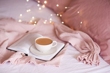 Lezzetli bir fincan kahve kağıdın üzerinde, parlak ışıkların üzerinde duruyor. İyi sabahlar. Kahvaltı.. 