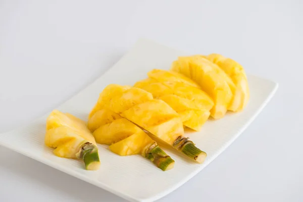 Pequeñas rodajas de piña y hojas en plato sobre fondo blanco — Foto de Stock