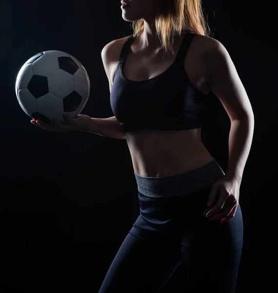 Mooie vrouw met een voetbal zwarte achtergrond — Stockfoto