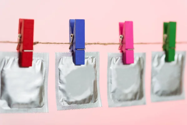 Arka plan ışığı ipte asılı prezervatif pembe.
