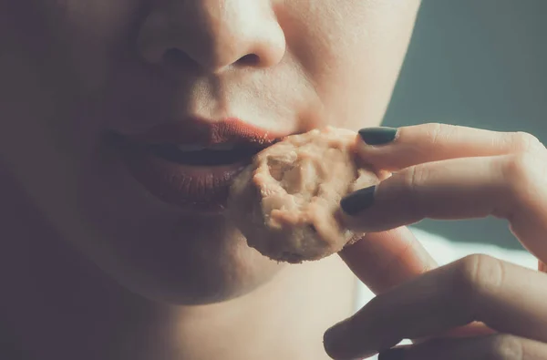 young woman eating a cookie in studio shot