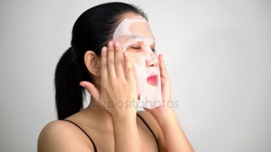 Genç kadının beyaz arka plan üzerinde yüzünde maske arındırıcı ile yüz maskesi sayfası yapması