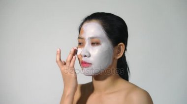 Genç kadın kil yüz maskesi peeling maskesi yüzünde beyaz arka plan üzerinde arıtma ile doğal