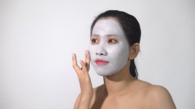 Genç kadın kil yüz maskesi peeling maskesi yüzünde beyaz arka plan üzerinde arıtma ile doğal