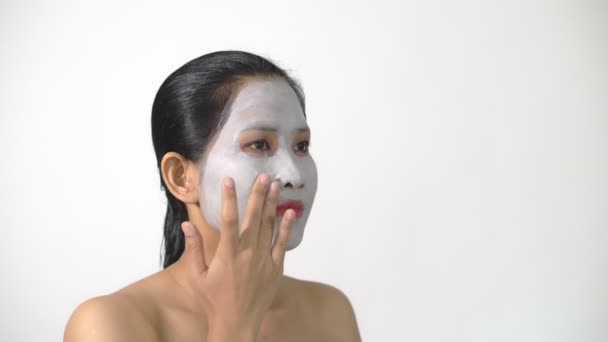 Mujer joven mascarilla de barro peeling natural con mascarilla purificadora en su cara sobre fondo blanco — Vídeos de Stock