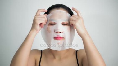 Genç kadının beyaz arka plan üzerinde yüzünde maske arındırıcı ile yüz maskesi sayfası yapması