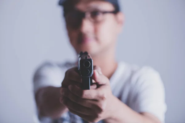 Joven asiático sosteniendo un arma apuntando a la pistola, con selectivo — Foto de Stock