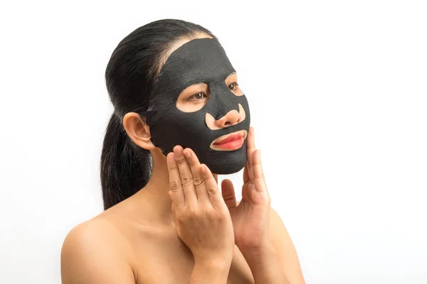Mladá žena, která dělá černá maska listu s čistící maska na — Stock fotografie