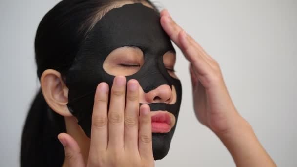 Jovem Mulher Fazendo Facial Folha Máscara Preta Com Máscara Purificante — Vídeo de Stock