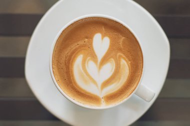 Tahta masada bir fincan sıcak latte sanat kahvesi.