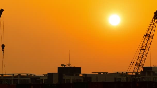 Time-lapse 4k: Jeřábi zvedání kontejnery běží pozadí západ slunce ve večerních hodinách. — Stock video