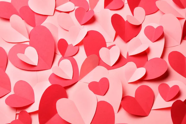 Куча вырезанных из розовой и красной бумаги сердец на розовом фоне — стоковое фото