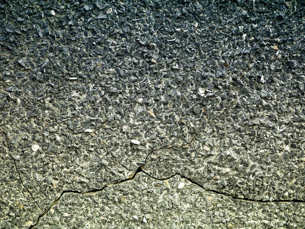 黒灰色のスタッコの背景に小さな小石と亀裂 — ストック写真