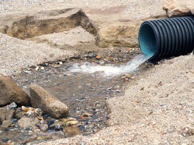 Pure clear water flows from a wide corrugated pipe. Eco-friendly background with clear water.