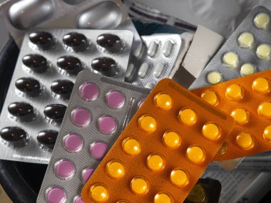 Plastic blisters with medicines fill the container. Blisters lie on top of each other. Tablets and capsules for various diseases. Multi-colored medical background.
