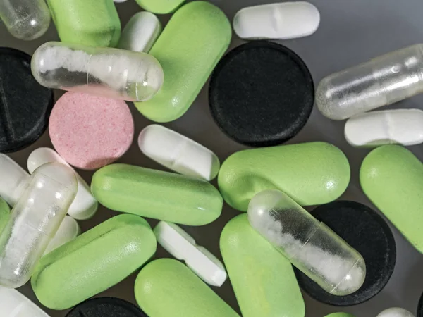 Capsules and compressed tablets for various diseases. Medical preparations close-up. Bright medical background.
