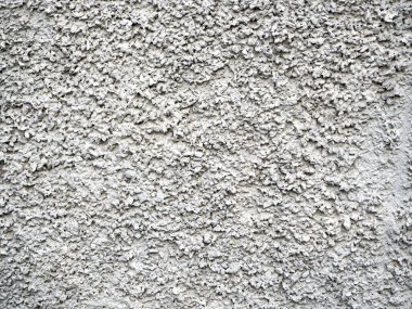 Açık gri taneli sıva, duvarda soyut bir desen oluşturuyor. Sakin taş arkaplan.