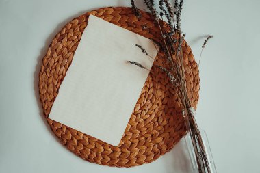 Soyutlama, beyaz bir masada bir hasır yuvarlak duruş ve üzerinde boş bir kağıt tabaka, metin, mor lavanta çiçekleri, üst görünüm, düz düzen, kopyalama alanı yatar. Metin için en az alan.