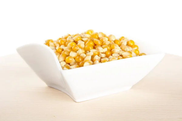 Salad-bowl full of dried raw corn on wooden table — Stock Photo, Image