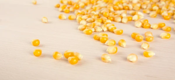 Scattered ripe dried yellow corn on wooden desk — Stock Photo, Image