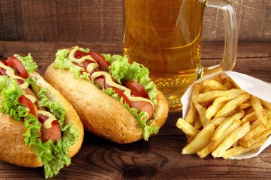 Sosisli sandviç bardak bira ile ahşap tahta üzerinde patates kızartması ile