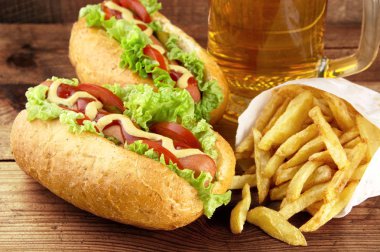 Sosisli sandviç bardak bira ile ahşap tahta üzerinde patates kızartması ile