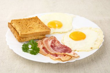 Dilim tost ile plaka üzerinde iki yumurtalı domuz pastırması