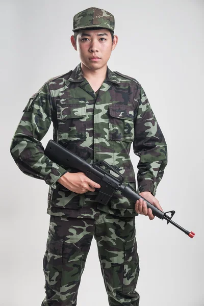 Asian soldier in green camouflage uniform with long gun — Stock Photo, Image