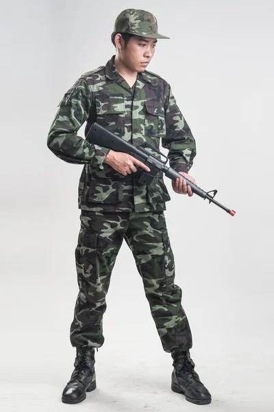 Asian soldier in green camouflage uniform with long gun — Stock Photo, Image