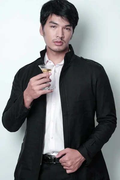 Asiatisk mann i svart jakke med et glass vin. – stockfoto