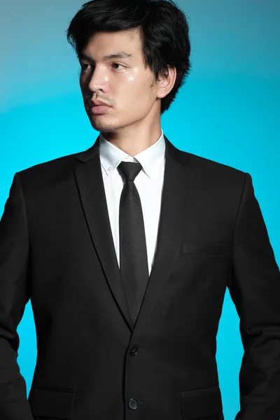 Pria Asia berjas hitam dan kemeja putih dengan latar belakang biru — Stok Foto