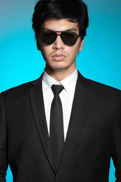 Asian man in black suit and white shirt on blue background — Stock Photo, Image