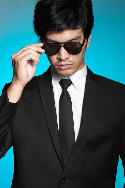 Asian man in black suit and white shirt on blue background — Stock Photo, Image