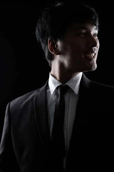 Aziatische man in zwarte formele pak in het donker — Stockfoto
