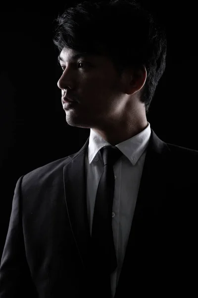 Asian man in black formal suit in the dark — Stock Photo, Image