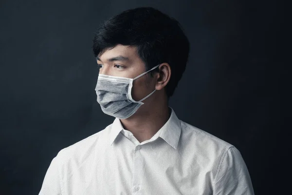 Asian man with medical mask on his face in black background - Studio portrait
