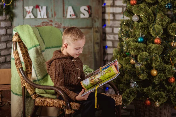Rapaz lê perto da árvore de Natal — Fotografia de Stock