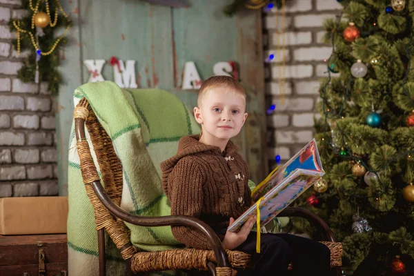 Jongen leest in de buurt van de kerstboom — Stockfoto