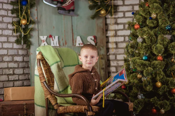 Jongen leest in de buurt van de kerstboom — Stockfoto