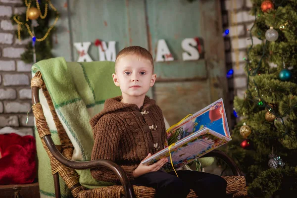 Boy reads near the Christmas tree — Stock Photo, Image