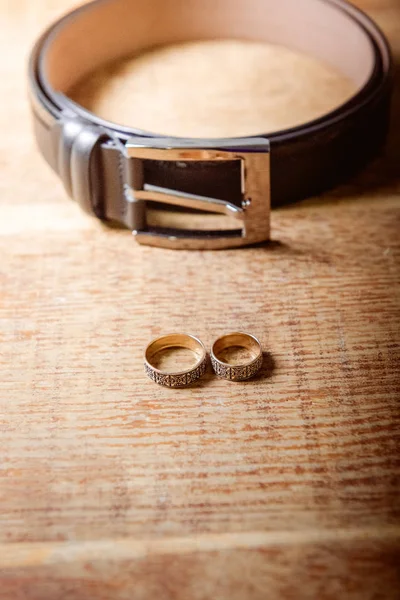 結婚指輪と木製のテーブルの男性のベルト — ストック写真