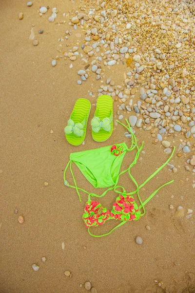 Swimsuit and flip flops on the sand — Stock Photo, Image
