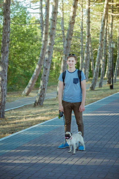 Young man with a pug in the park — Stock Photo, Image