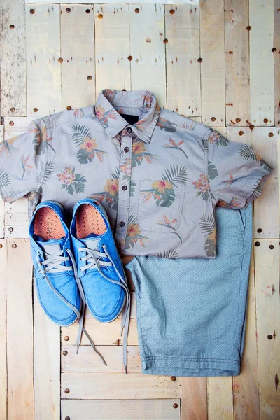 Scarpe da ginnastica e una camicia su sfondo di legno Foto Stock